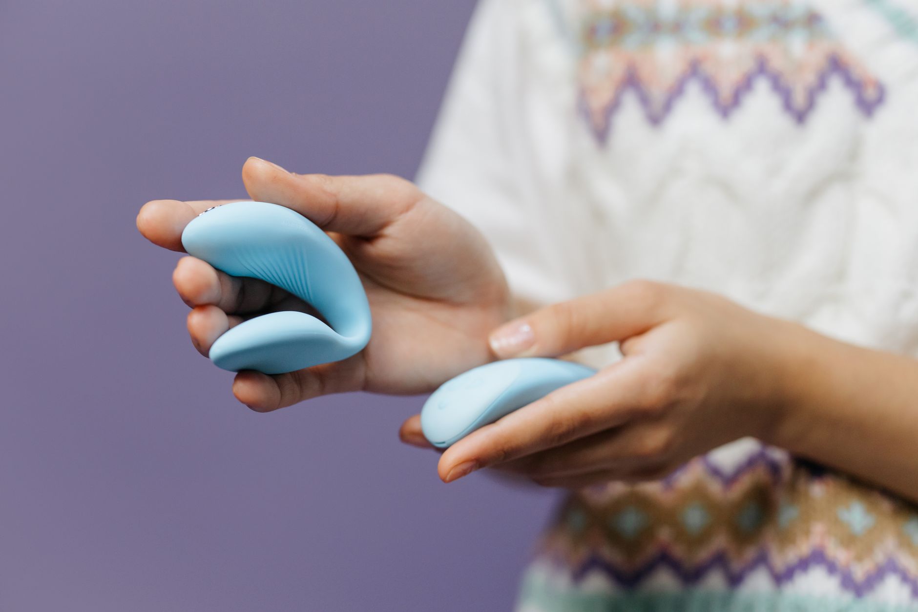Young couple standing together indoors holding a blue vibrator, symbolizing modern intimacy and partnership